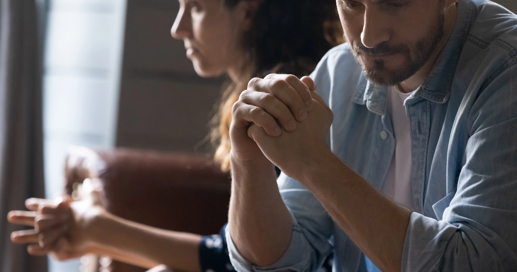 man looking down frustrated while a woman sits with hands balled