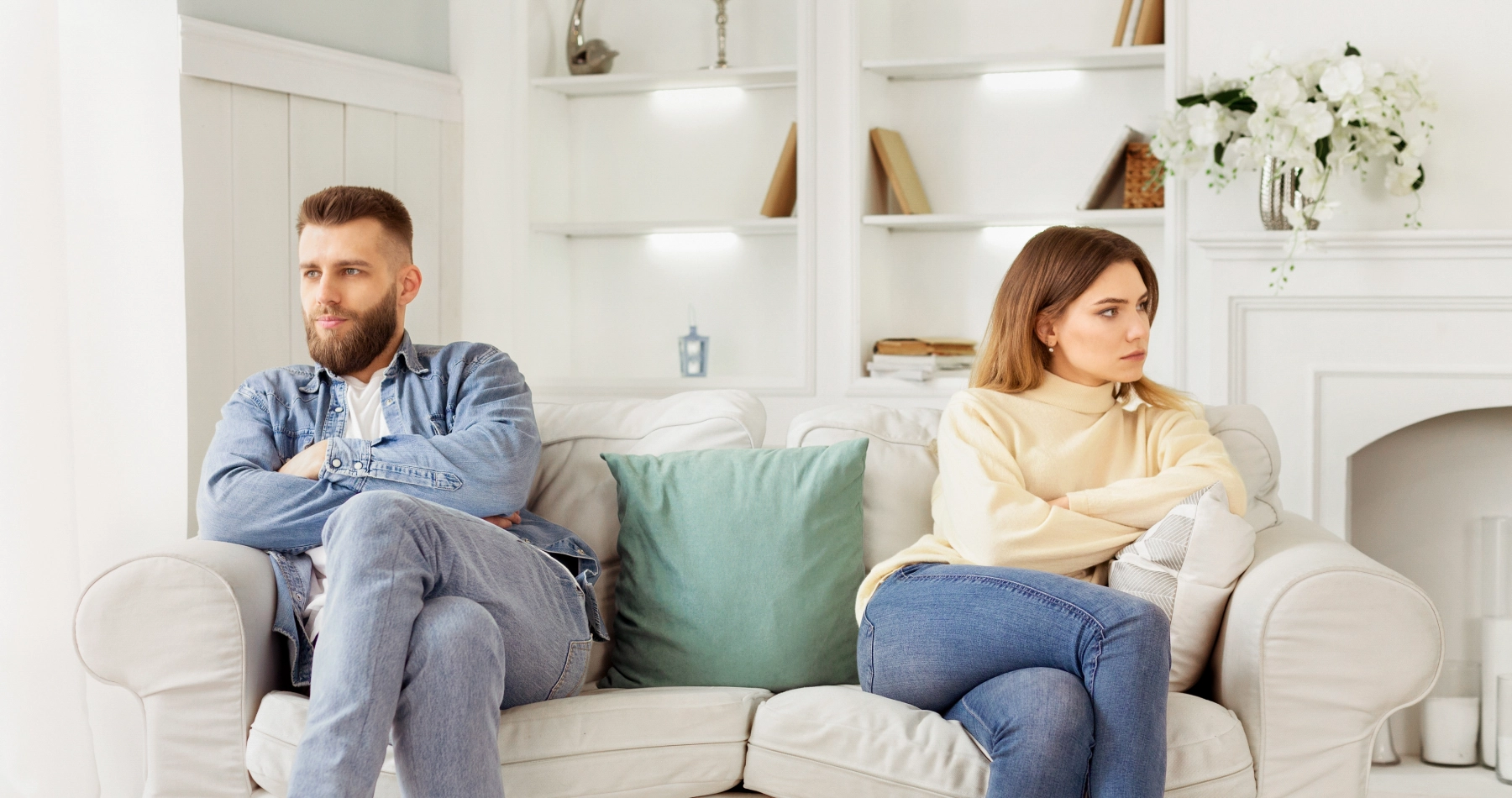 husband and wife on opposite sides of the couch looking away from each other